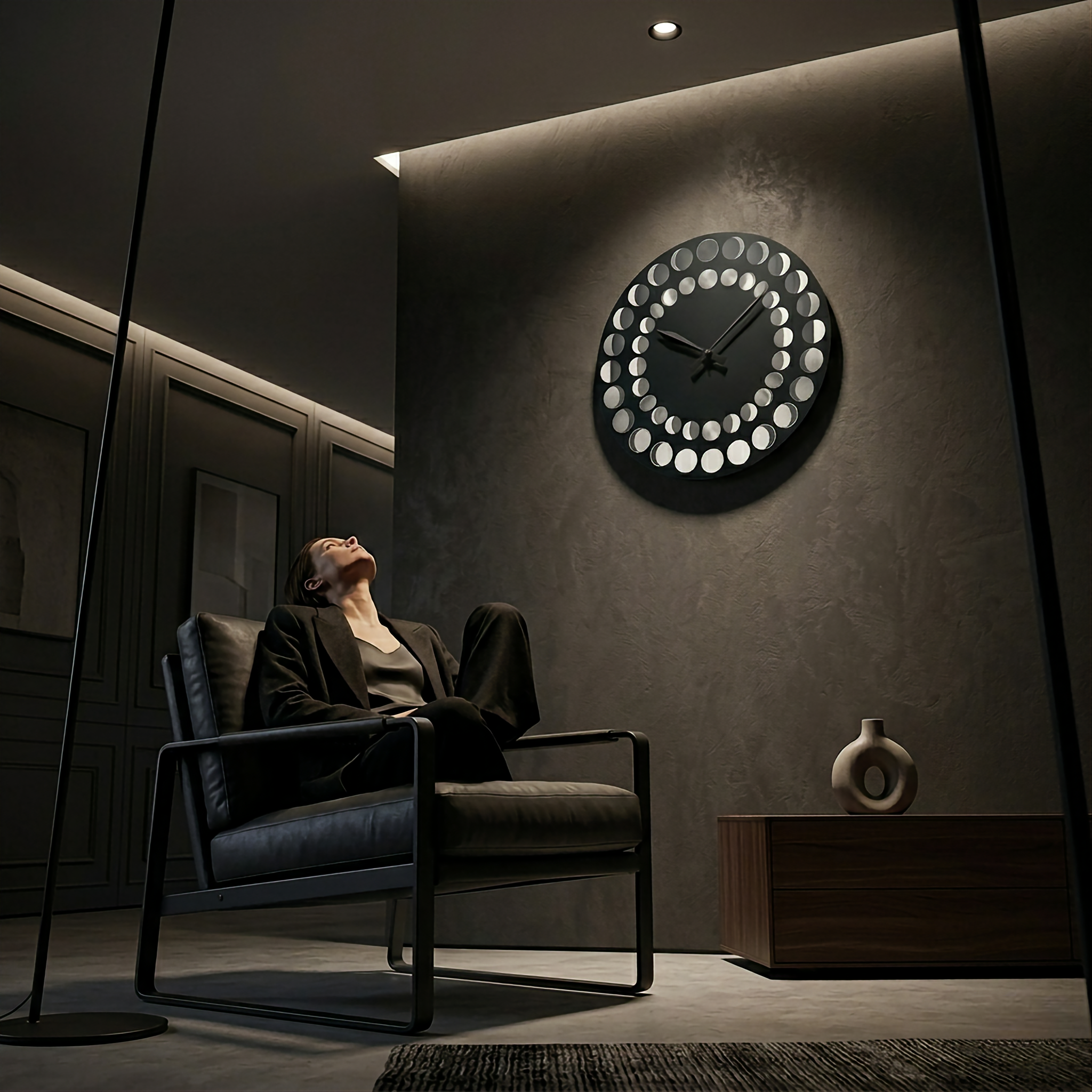 Person sitting in a modern chair in a dimly lit room with a decorative wall clock.